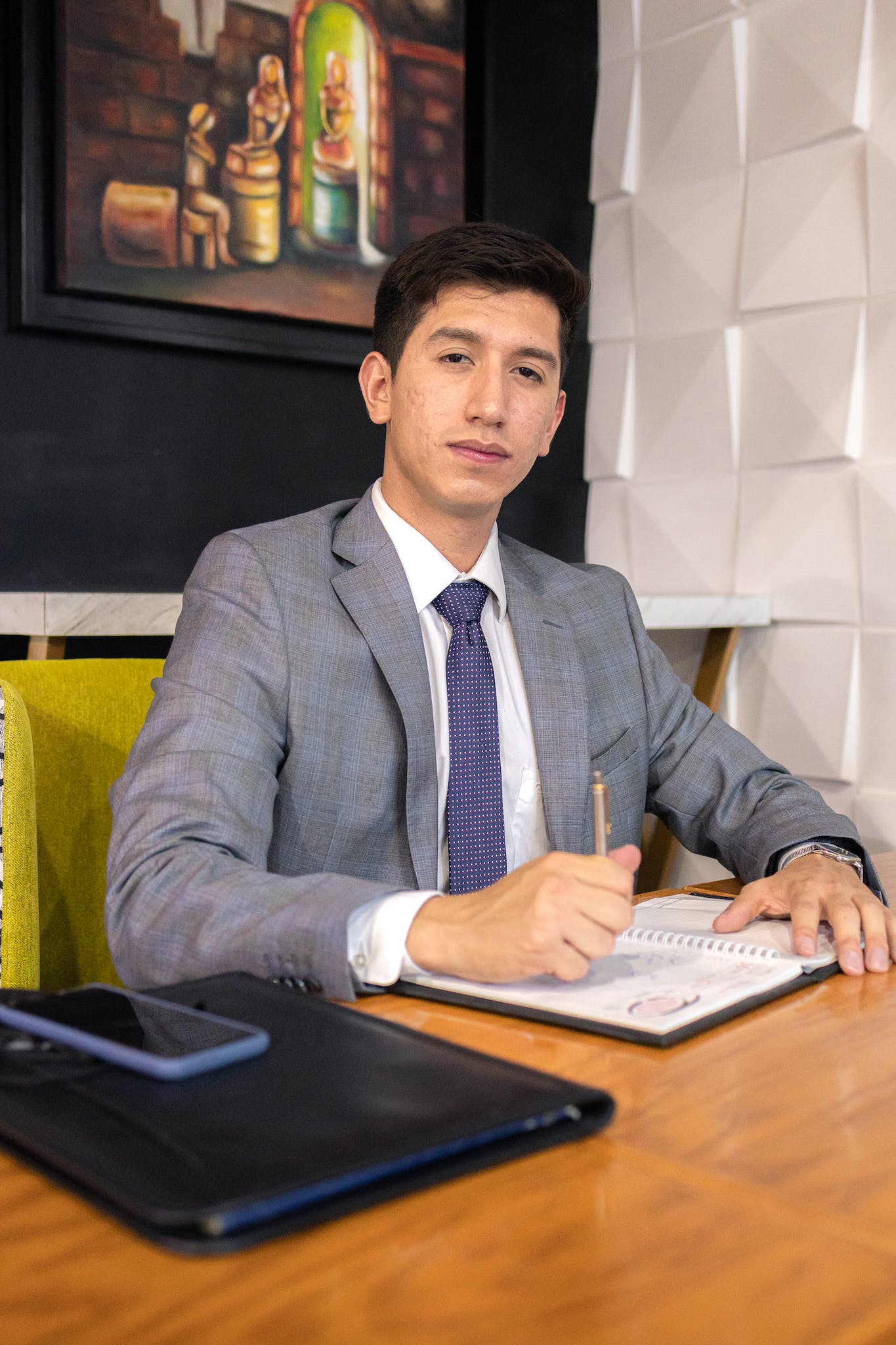 A man in a suit sitting at a desk with a pen and paper